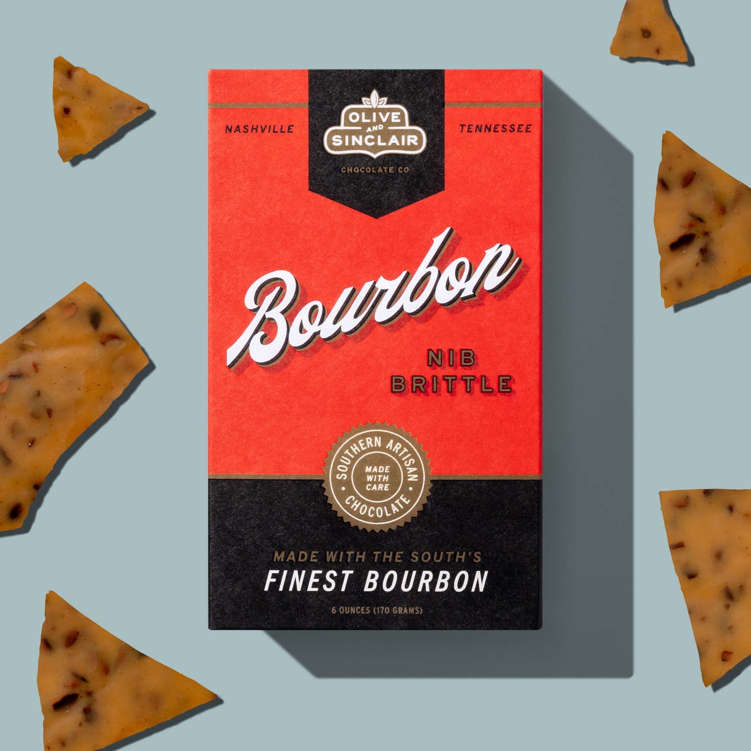 Box of Bourbon Nib Brittle with brittle pieces on a light blue background