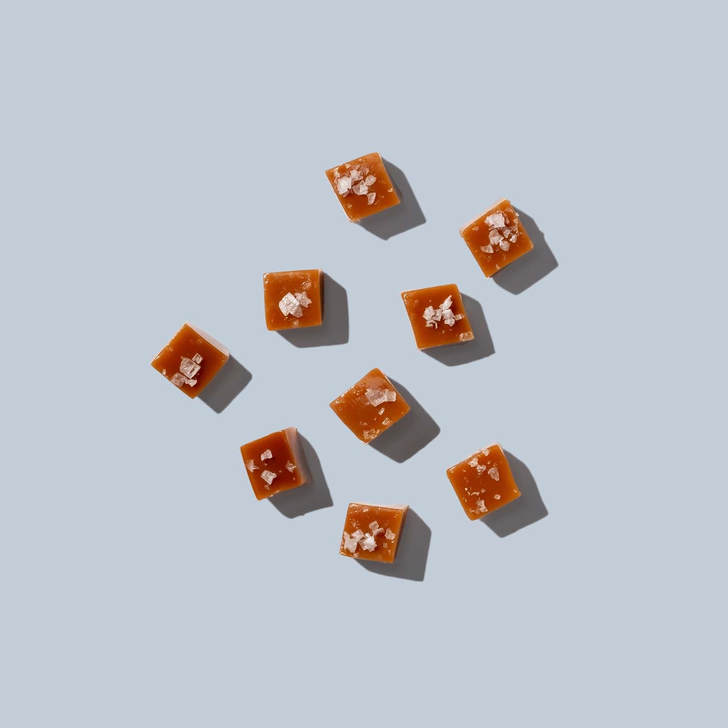 Square pieces of caramel with sea salt on a light blue background