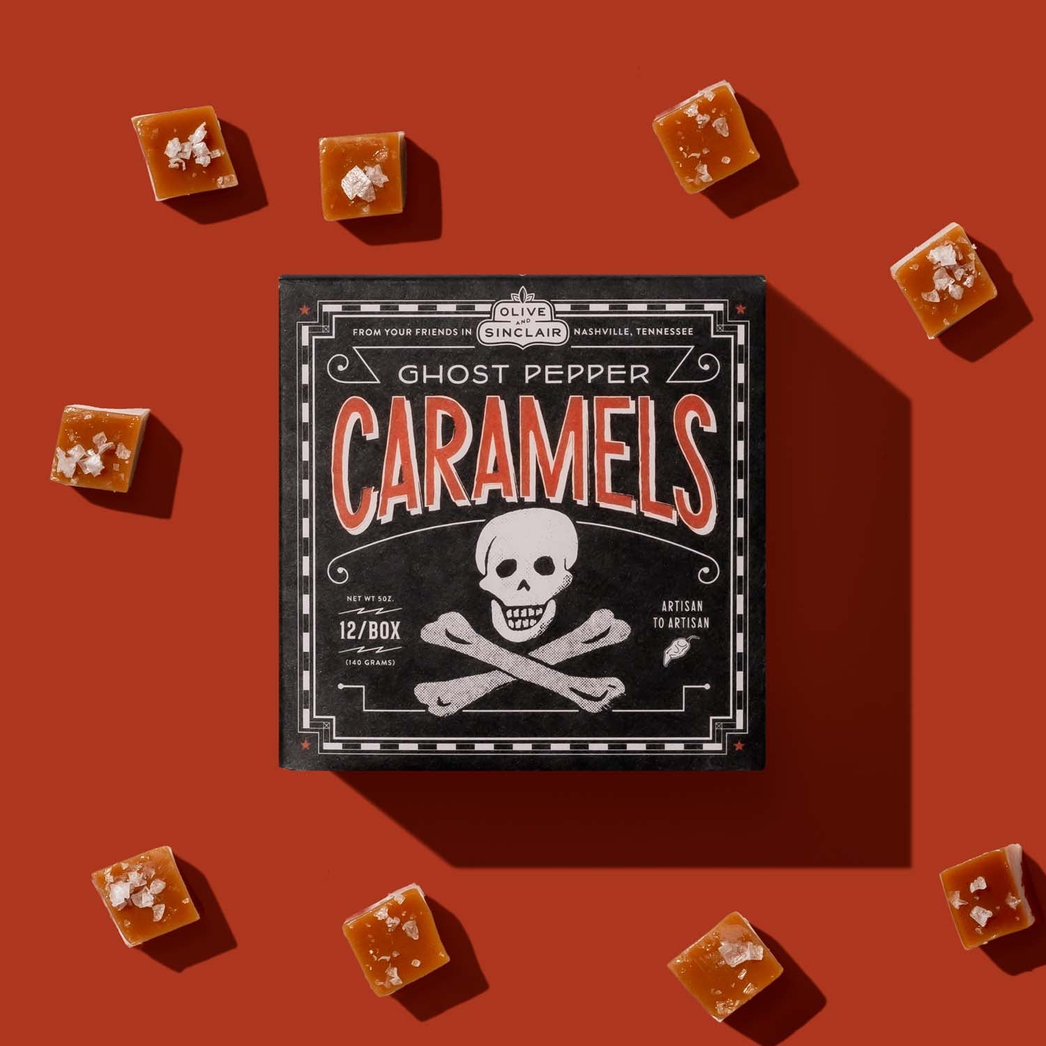 Box of Ghost Pepper Caramels with scattered caramels on a red background