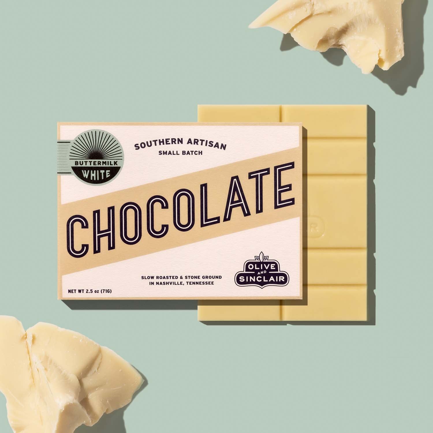 Bar of Olive and Sinclair White chocolate with cocoa butter chucks in the background 