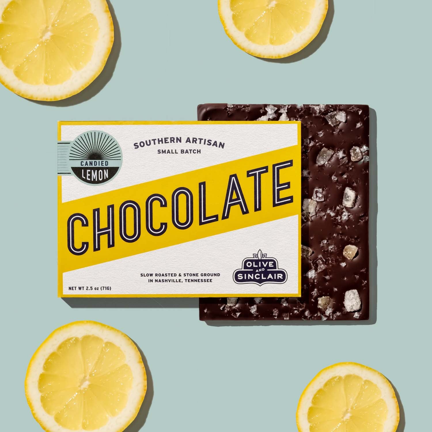 bar of Olive Sinclair candied lemon chocolate with candied lemons on a light blue background