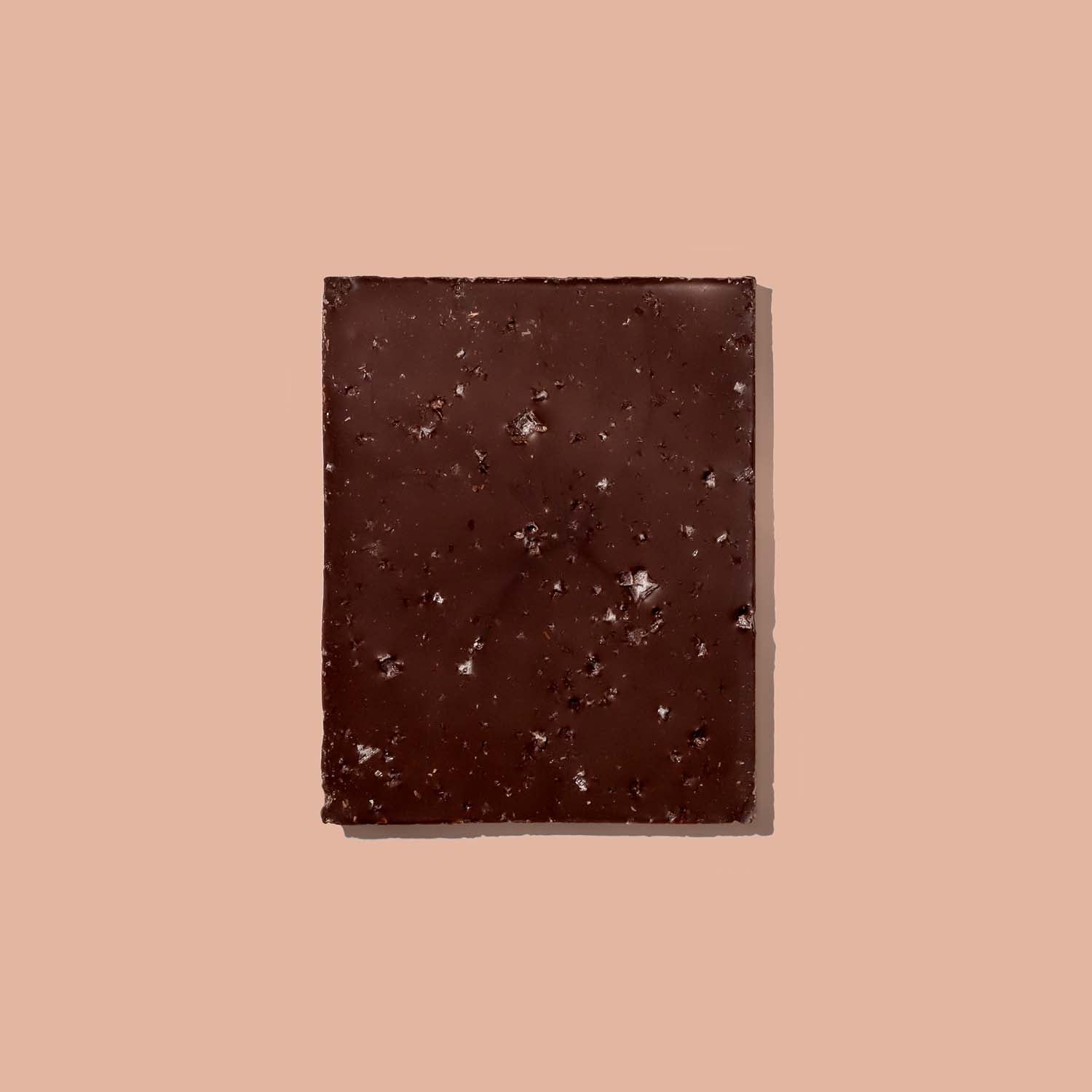 Dark chocolate bar with visible  Sea Salt chunks on a pink background