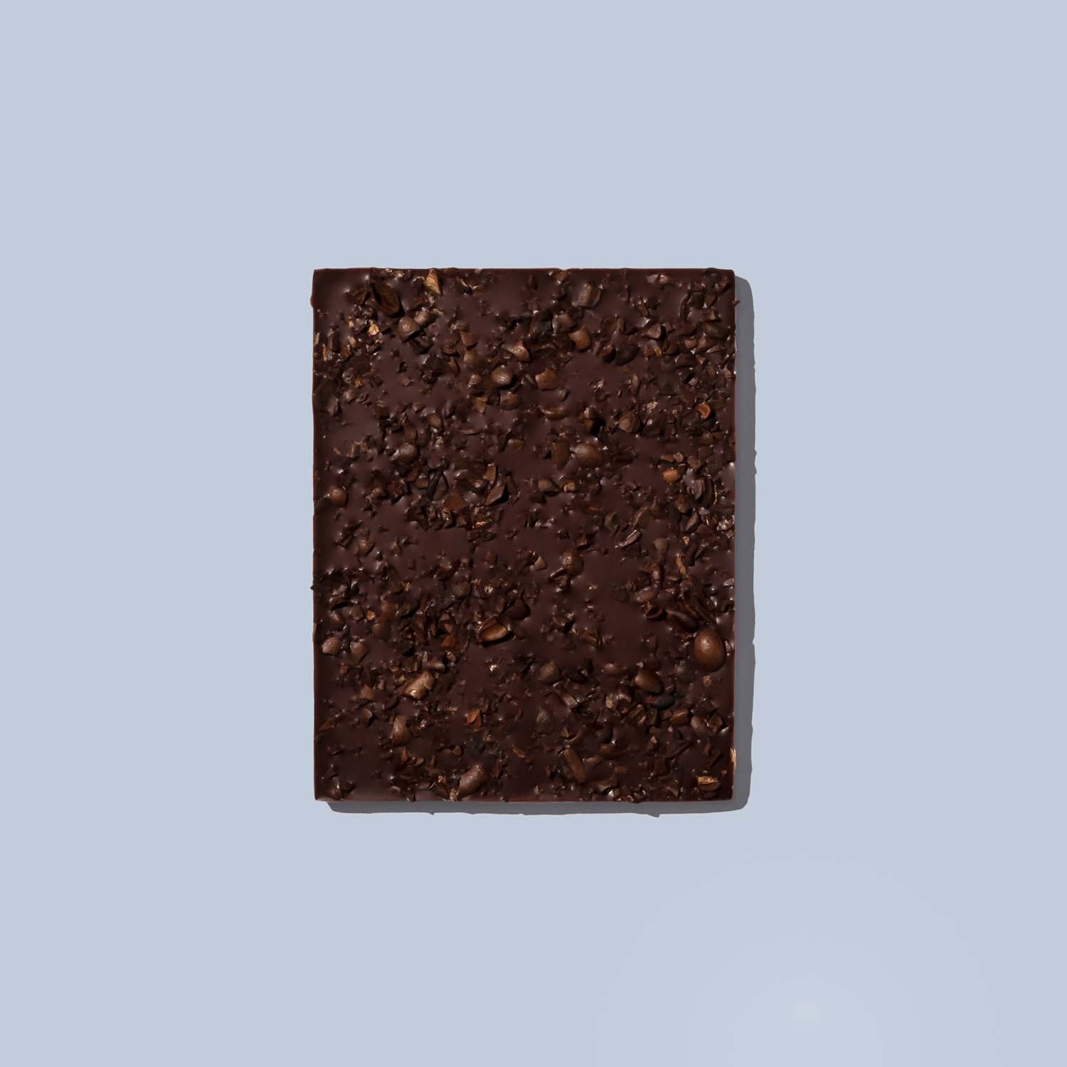 Dark chocolate bar with visible cocoa nibs on a light blue background